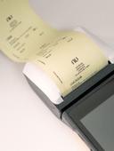 Imagem de uma maquininha de cartão imprimindo um comprovante de pagamento.